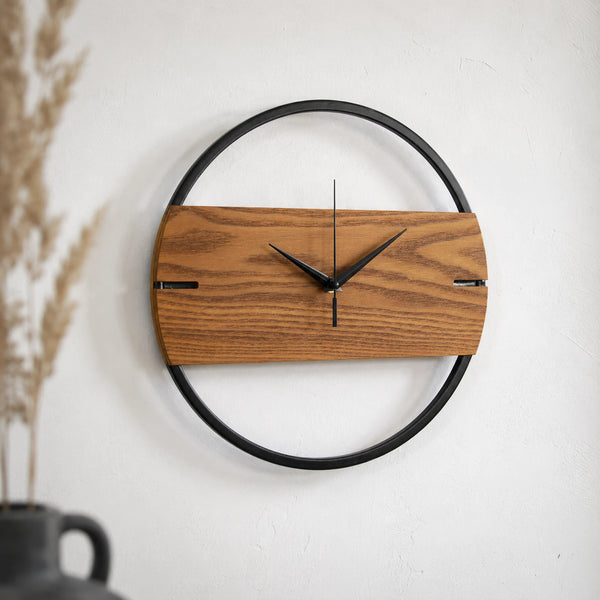 Moderne Wanduhr aus Holz und schwarzem Metall auf weißer Wand